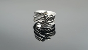 Détail d'une bague plume vintage en argent avec finition oxydée sur surface réfléchissante noire