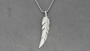 Detailed close-up of a silver feather pendant showing intricate metal textures and box chain