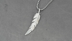 Close-up of silver feather pendant with detailed texture on a classic steel box chain