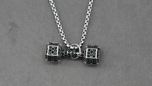 Gros plan d'un pendentif haltère en argent avec zircons noirs sur chaîne box