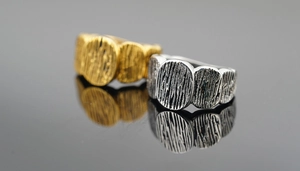 Macro shot of gold and silver rings with textured bark pattern on black reflective surface
