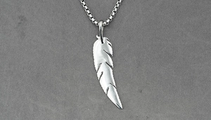 Detailed macro view of the silver feather pendant with intricate textured engraving