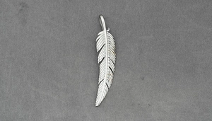 Detailed macro view of a silver feather pendant with intricate textured engraving details