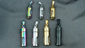 Capsule cremation pendants in various finishes with clear windows on dark fabric