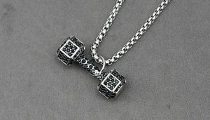 Gros plan d'un collier pendentif haltère argenté serti de zircons noirs brillants