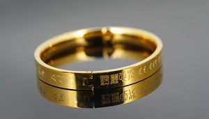 Macro shot of gold stainless steel bangle with engraved scripture and mirror finish