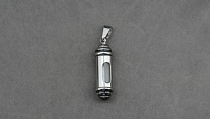 Macro shot of silver stainless steel capsule pendant with black rings and clear window