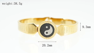 Detail of gold titanium steel bangle with Yin Yang symbol and engraved scriptures