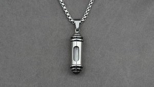 Close-up of silver capsule pendant with transparent window on a box chain necklace