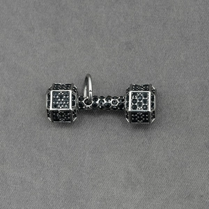 Pendentif haltère argenté avec micro-cristaux noirs sur fond en tissu texturé gris