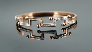 Gros plan d'un bracelet ouvert doré rose avec motifs géométriques et zircons brillants