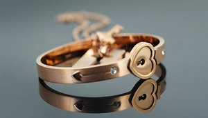 Macro shot of rose gold heart lock bracelet and key necklace with zircon accents