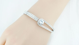 Detailed close-up of a silver buckle bangle with pavé zircons and a large central crystal