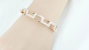 Détail du bracelet géométrique en or rose avec zircons porté au poignet sur velours