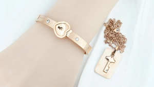 Rose gold heart lock bracelet and key necklace set with zircon stones on white background