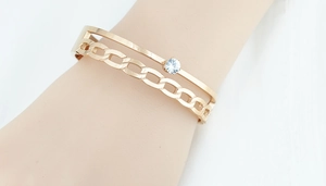 Détail d'un bracelet double épaisseur en or rose avec pierre de zircone et maille cubaine