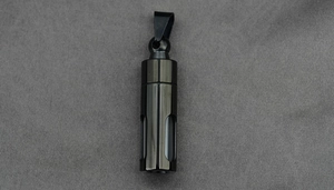 Detail of black cylindrical cremation pendant with clear window on grey texture