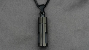 Close-up of black cylindrical perfume urn pendant on a matching box chain necklace