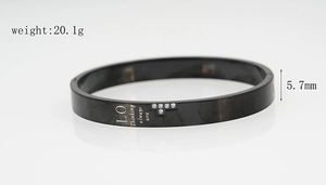 Détail du bracelet en acier titane noir avec texte gravé et cristaux blancs en forme de T