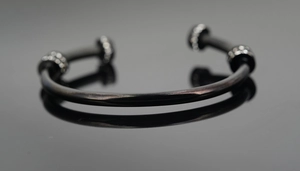 Gros plan d'un bracelet en acier titane noir avec diamants sur un fond réfléchissant