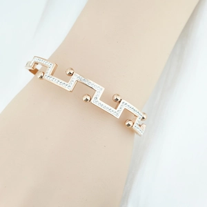 Bracelet jonc géométrique or rose avec motif de remparts et pavé de cristaux sur bras