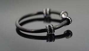 Gros plan d'un bracelet en acier titane noir avec anneaux argentés sertis de cristaux