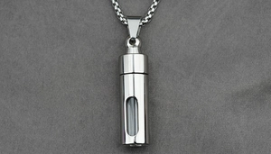 Detailed macro of silver cremation pendant with vertical glass window and polished chain