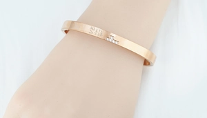 Gros plan d'un bracelet jonc en or rose avec cristaux et gravure porté au poignet