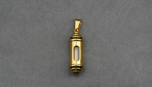 Detailed view of a gold capsule pendant with clear window for memorial or essential oils