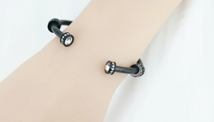 Détail d'un bracelet en acier noir texturé avec des extrémités ornées de cristaux