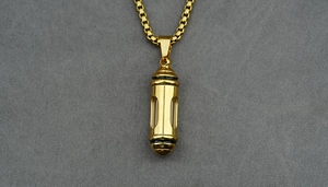 Detailed close-up of golden capsule pendant necklace with a clear window and box chain