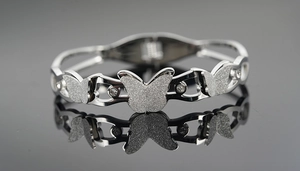 Detailed macro shot of silver butterfly bangle with frosted texture and clear zircons