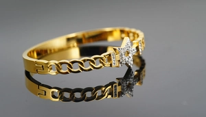 Detail of gold-plated bangle with a sparkling crystal star and chain link design