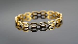 Close-up of gold titanium steel bracelet featuring detailed woven texture and pavé stones