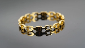 Detailed macro view of gold-plated rectangular link bracelet with shimmering zircon stone