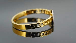 Detail of gold titanium steel bracelet featuring Cuban link design and sparkling crystal inlay