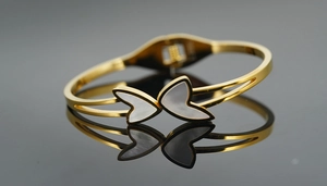 Detail of gold titanium steel bangle with white mother-of-pearl butterfly inlay
