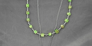 Detail of layered turquoise cube bead necklace with silver steel beads on fabric