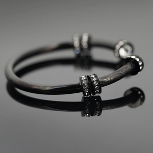 Bracelet moderne en acier titane noir avec trois anneaux argentés sertis de zircons clairs