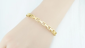 Close-up of a polished gold braided link bracelet with rectangular woven patterns
