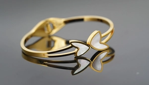 Close-up of golden stainless steel bracelet featuring white mother-of-pearl butterfly inlay