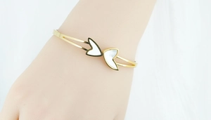 Detailed view of a gold open heart cuff bracelet featuring white mother-of-pearl inlays