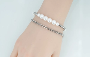 Close-up of double-layer bracelet with white pearls and silver curb chain on wrist