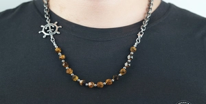 Detail of nautical拼接项链 with silver ship rudder and tiger eye stones on black tee