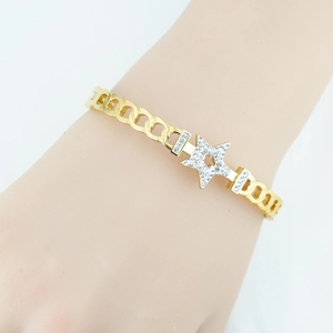 Luxury gold star bracelet with crystal pavé on metal chain worn on a female wrist