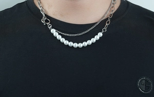Detail of layered titanium steel chain necklace with white pearls and a vintage OT buckle clasp