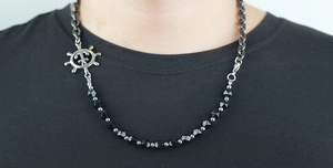 Detail of nautical rudder pendant on black faceted bead and silver chain necklace