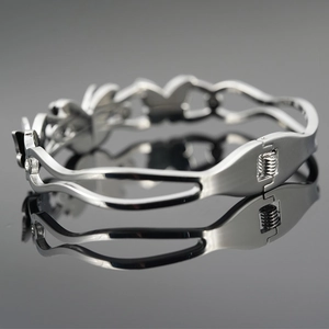 Polished silver titanium steel bracelet with butterfly cut-out design on a reflective surface