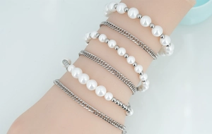Détails d'un ensemble de bracelets avec perles blanches et chaînes à mailles argentées