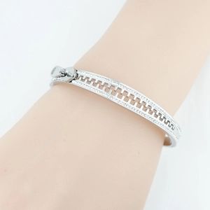 Silver zipper bangle with sparkling zircon stones on a female wrist, stylish metal jewelry